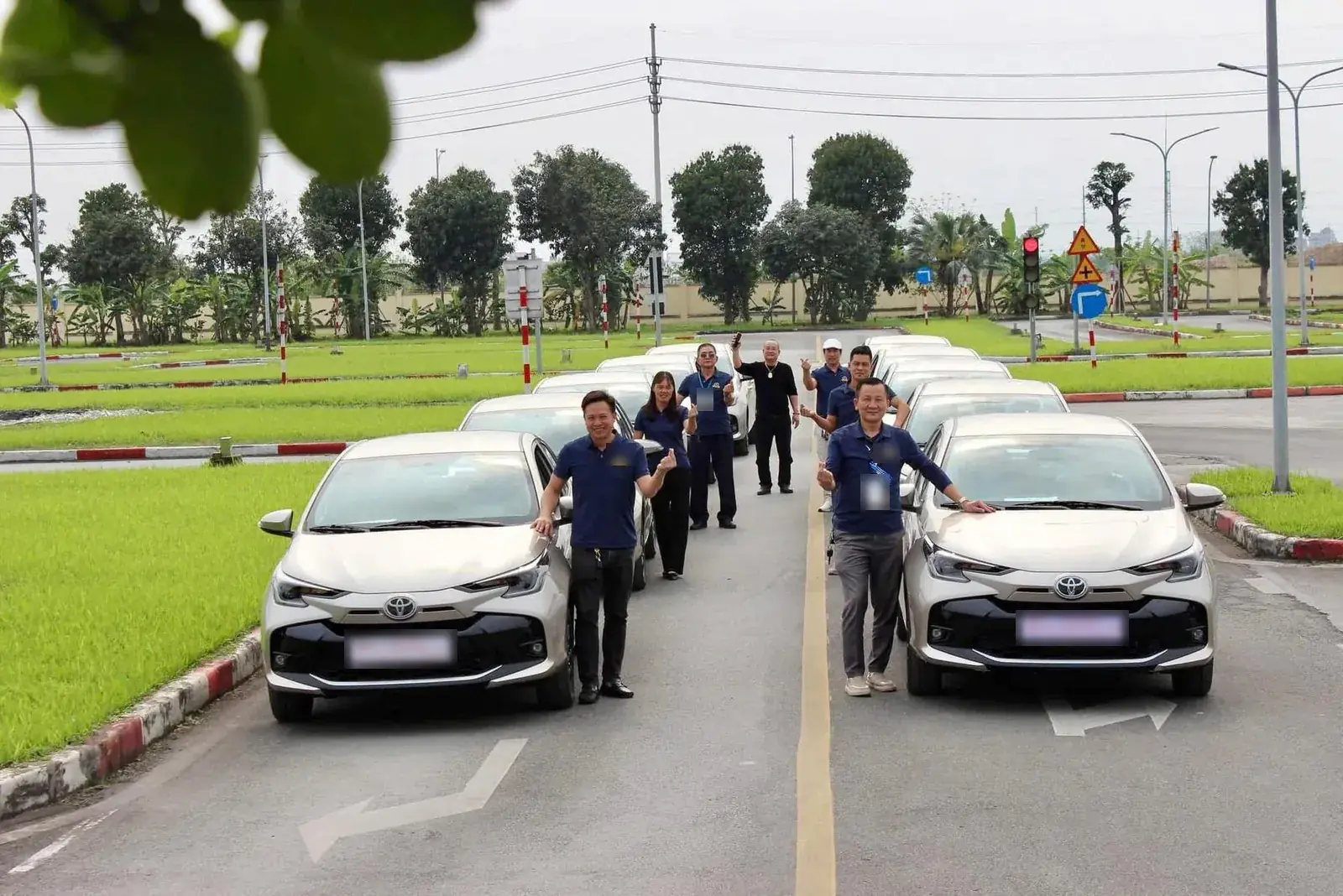 Giáo viên đứng cạnh dàn xe tập lái hạng B trên sân tập